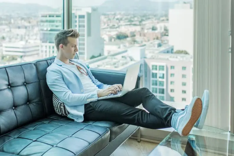 man sitting on couch using a laptop